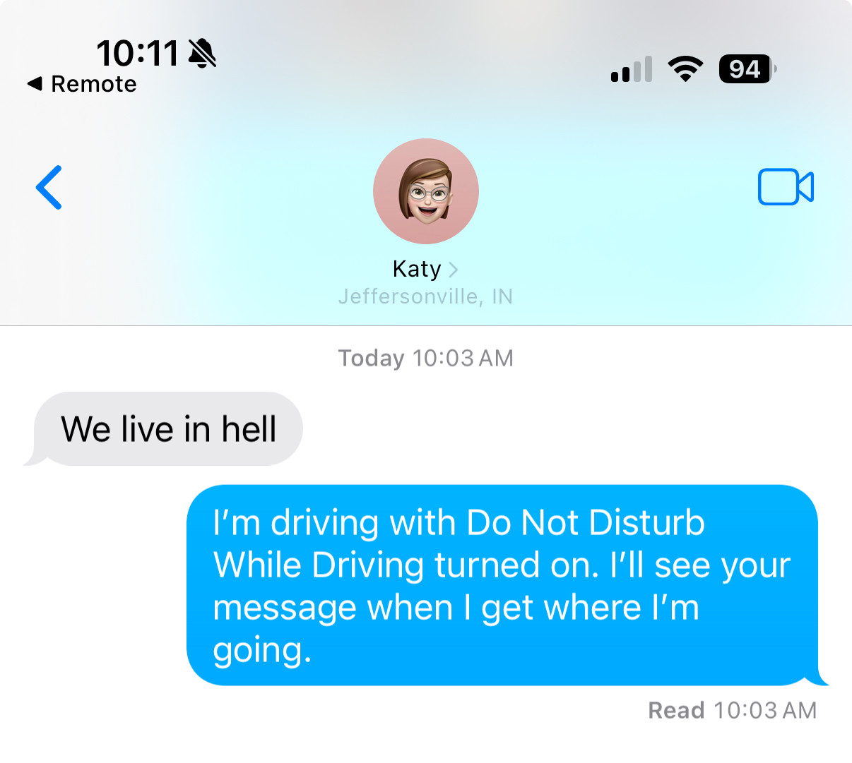 Screenshot of an iMessage conversation. The other person messaged "We live in hell." The screenshotter's phone auto-replied "I'm driving with Do Not Disturb While Driving turned on. I'll see your message when I get where I'm going."