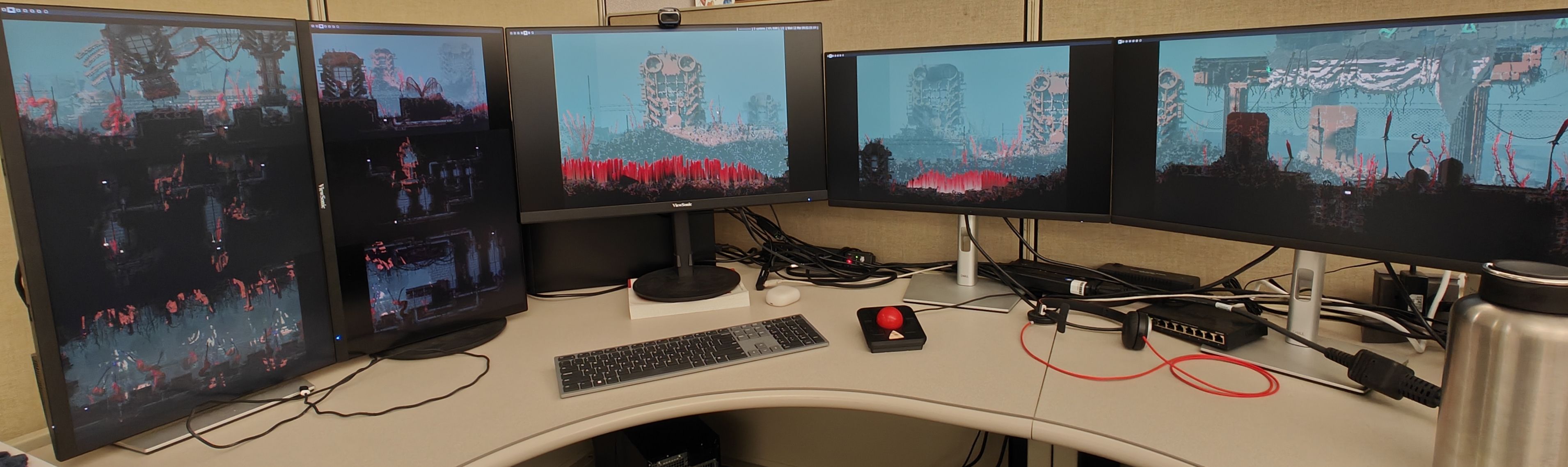 A picture of a computer setup. There are multiple monitors each only displaying a wallpaper, which is stretched across all of the monitors.