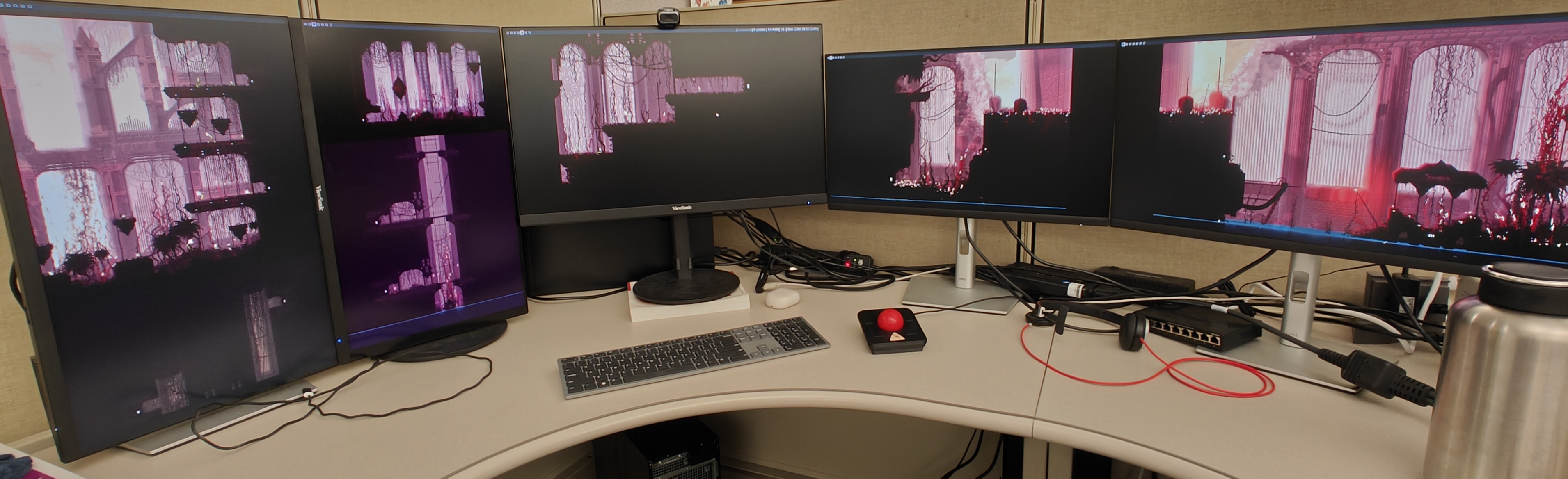 A picture of a computer setup. There are multiple monitors each only displaying a wallpaper, which is stretched across all of the monitors.
