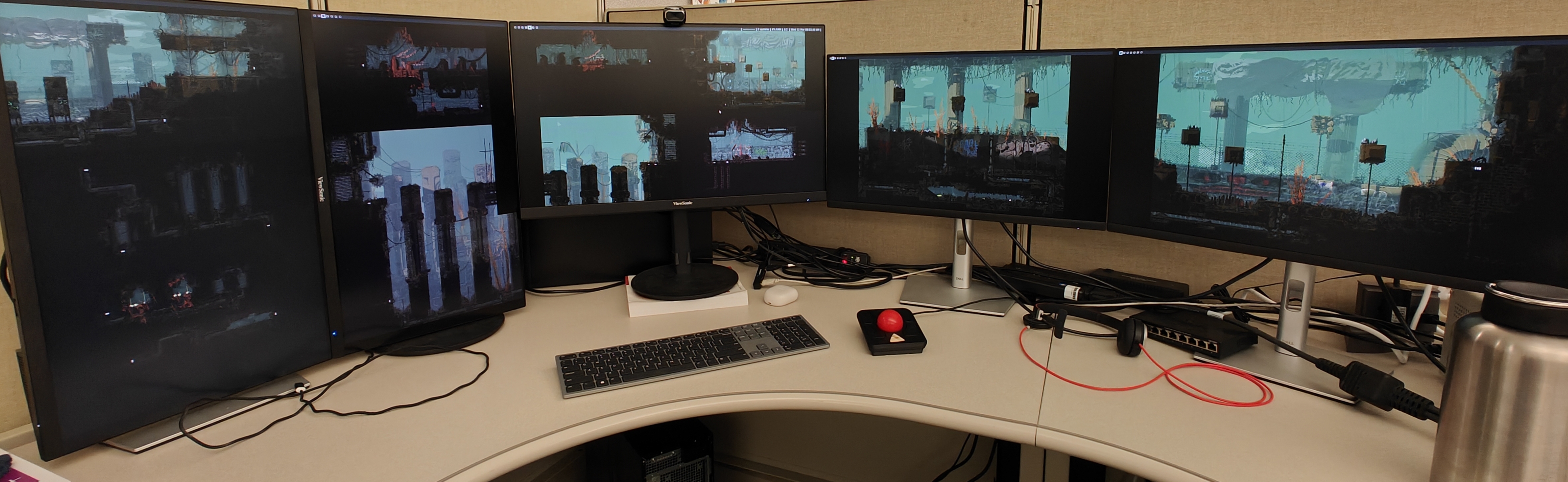 A picture of a computer setup. There are multiple monitors each only displaying a wallpaper, which is stretched across all of the monitors.